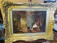 Full front view of framed oil painting showing interior scene and ornate gilt frame