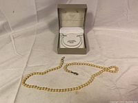 Photo showing the pearl necklace laid out with the original box behind it.