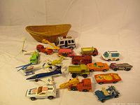 Wide shot of all toy vehicles including cars, trucks, helicopters and a Navy jet with a woven basket in background.