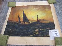Full front view of the oil on canvas painting with some green weights holding corners, showing the finished artwork of boats at sunset.