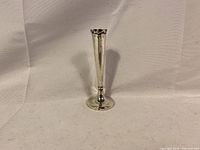 Full view of the sterling silver candlestick showing tall slender profile, round base, and smooth tapered stem.