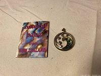 Full view of the pendant alongside a small card reading 'natural paua from New Zealand'