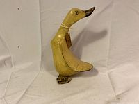 Full view of vintage wooden duck figurine standing upright, cream paint with dark brown beak, visible age cracks on surface, tag around neck.