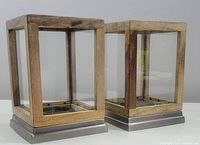 Two Hearth & Hand lantern style candle holders side by side showing wood frame, glass panels, and metal base