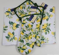 Full set of lemon themed kitchen linens including oven mitt, pot holders, and tea towels arranged on flat surface to show pattern and included items.
