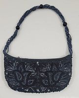 Full front view of black evening bag with twisted beaded strap and bead/sequin floral pattern.