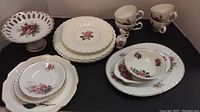 Overview showing the set of cups and various plates, bowls with rose patterns