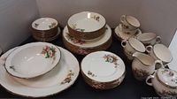 Full set of plates, bowls, cups, cream and sugar set displayed in white backdrop.