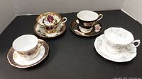 All four cups and saucers arranged for full view showing color and design variety.