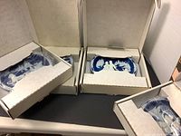 Four Christmas cameo 3D plates made of Incolay Lapis stone in original boxes with protective covers, showing the blue and white raised Christmas-themed relief scenes.
