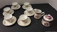 Full view of all items in the set: six cups with matching saucers, plus creamer and sugar bowl.