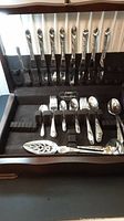 Full set of silver-plated flatware in Bridal Wreath pattern, organized in black velvet-lined box with knives, forks, spoons and serving pieces visible.
