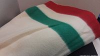 Folded cream-colored wool blanket showing red and green stripes