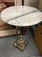 Front overview photo showing the round marble top and ornate brass stand with red glass dangles hanging from it.