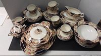 Full overview of the china set showing stacked plates, cups, covered serving bowl, teapot, and platters, highlighting design and condition.