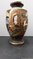 Front view of vase showing detailed figure with metal highlights on black porcelain