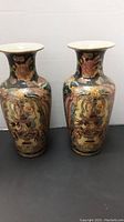 Pair of matching decorated tall ceramic vases with flared rim and narrow neck.