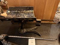 Side view of the black heavy-duty metal balance scale marked C.P.O. showing overall structure and weighing platform.