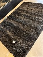 Full view of the black and grey thick shag rug laid out showing size and texture