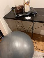 DVD player on a table with power cords, exercise ball on the ground