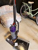 Upright Dyson DC51 vacuum standing beside sealed Total Clean Kit box on concrete floor.