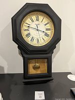 Front view of Kieningder chime clock showing octagonal black frame and cream dial with Roman numerals.