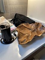 Large carved wood bowl with organic shape on countertop alongside a black electric coffee grinder with cord.