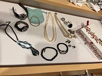Photo showing array of jewellery including bracelets, rings, necklaces, brooches, and two watches.