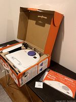 Neato Botvac 80 robot vacuum in original box with instruction manual on table.