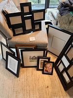 Photo showing all 10 picture frames arranged on a chair and the floor, including multi-photo collage frame and various sizes in black and brown.