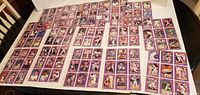 Front side of multiple baseball cards in purple borders laid out on a table, showing player images and details.