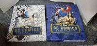 Book and slipcase side by side showing front designs with iconic DC characters