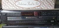 Front view of Sony 5-disc CD changer showing control buttons, CD tray, and brand markings.