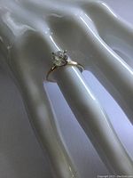 Close-up of the 14K gold solitaire ring on a white mannequin hand highlighting the thin band and diamond setting.