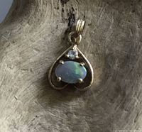 Front view of the heart-shaped pendant showing opal cabochon and diamond chip set in 9ct gold.
