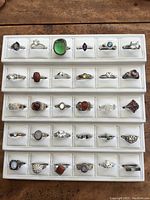 Four white display trays holding 30 assorted sterling silver rings