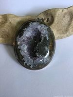 Front view of the oval Ocean Jasper crystal geode pendant featuring amethyst-like crystals inside a sterling silver frame.