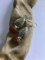 Pair of vintage sterling silver earrings with teardrop design and oval carnelian stones displayed on a wood background