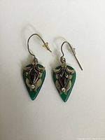 Pair of green onyx tear drop silver earrings with garnet and crystal stones shown from front, detailing the decorative silver and stone setting.