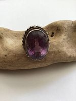 Close-up of the top of the ring showing the large oval faceted amethyst gemstone with a beaded silver border.