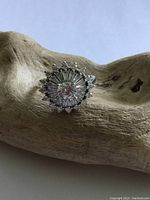 Front view of sterling silver ring showing round clear crystal set in flower-like design.