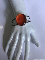 Front view of vintage sterling silver cuff bracelet on display hand model, showing large oval red center stone.