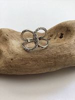 Front side view of a sterling silver ring with an infinity symbol design, with one side set with small clear stones.