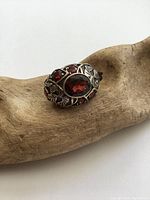 Front view of the sterling silver garnet ring showing the large central oval garnet surrounded by smaller garnets and detailed flower and leaf silverwork.