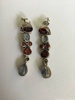 Front view of earrings showing garnet and moonstone stones, displaying color and shape.