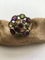 Front view of the ring showing the arrangement of multiple colored gemstones set in silver.