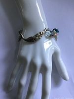 Sterling silver bracelet with a mermaid charm and blue and red bead details shown on a mannequin hand.