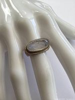 Sterling silver ring with oval moonstone on a white mannequin hand, showing stone and band details.