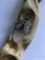 Front view of pendant showing rose quartz teardrop shape, silver decorative setting with garnet stone centered in front