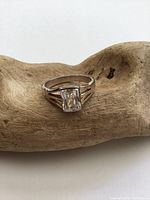 Front view of sterling silver solitaire ring with rectangular clear crystal, showing setting and tarnish.